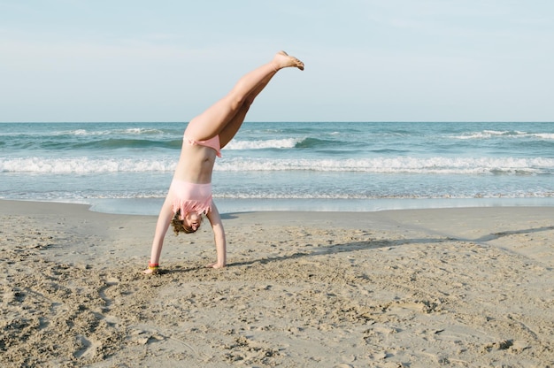 teenager performing cartwheel at beach against sky