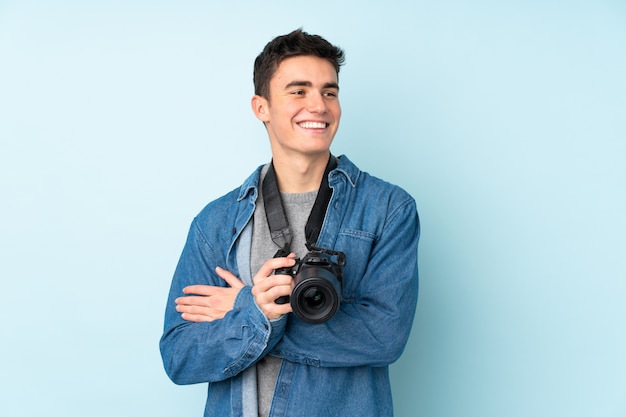 Teenager photographer man on blue wall laughing