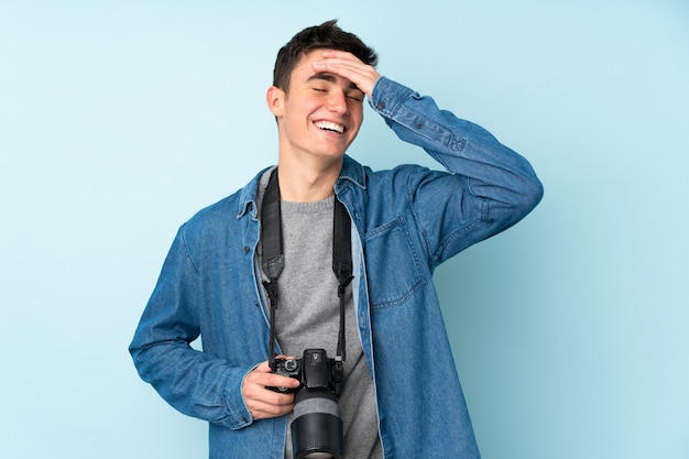 Teenager photographer man isolated on blue laughing