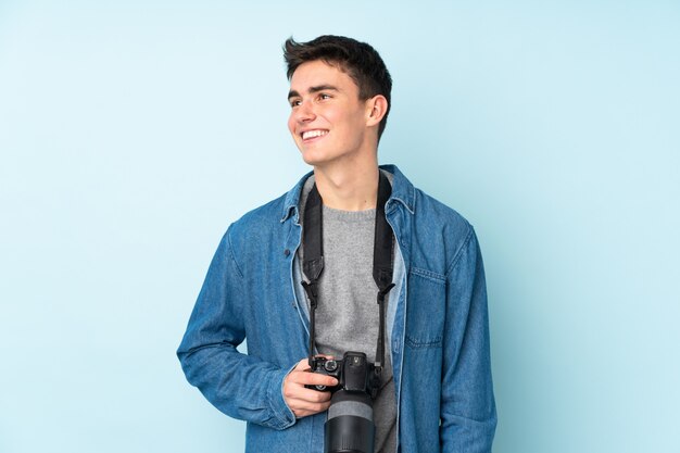 Teenager photographer man isolated on blue