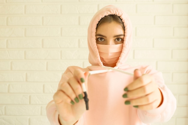 teenager in a pink mask for protection against 2019-ncov covid-19 at home in social isolation.