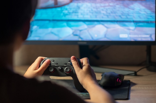 A teenager plays computer games. He holds a joystick in his hands