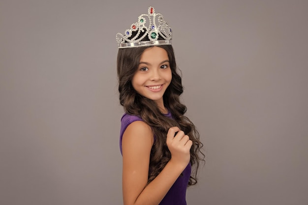 Teenager princess child celebrates success win and victory teen\
girl in queen crown happy girl face positive and smiling\
emotions