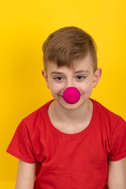 Teenager in red tshirt with clown nose on yellow background vertical frame