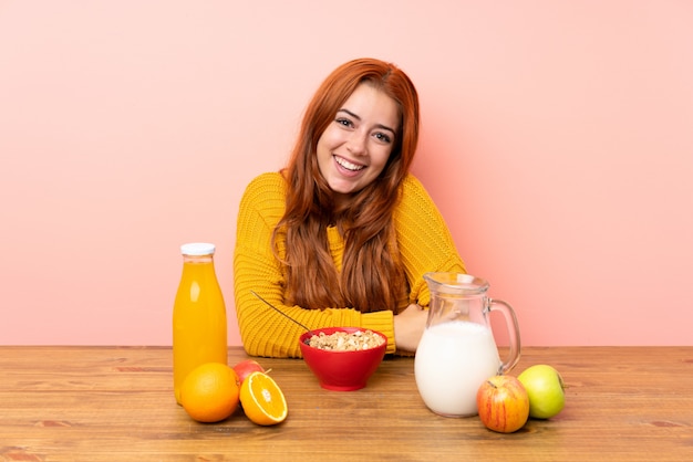 Teenager redhead girl having breakfast in a table laughing