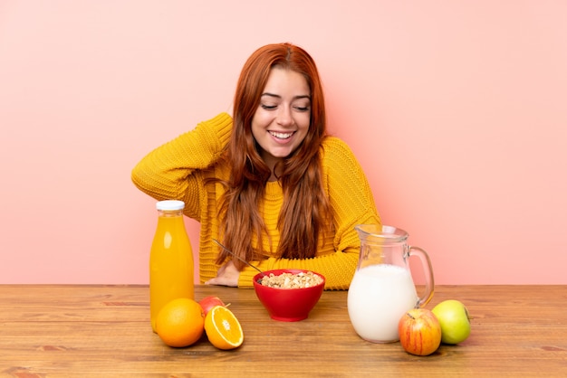 Teenager redhead girl having breakfast in a table laughing