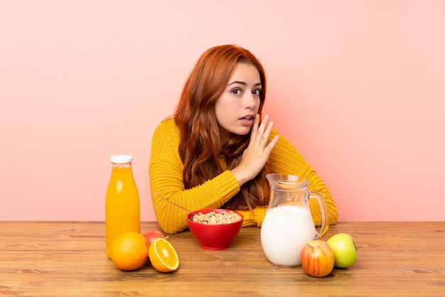 Teenager redhead girl having breakfast in a table whispering something