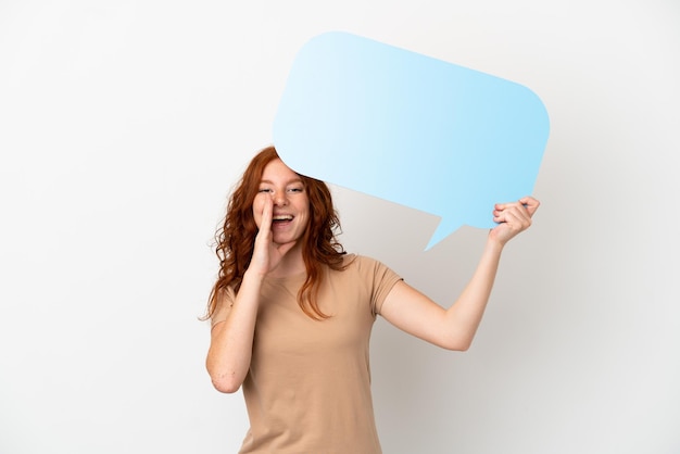 Teenager redhead girl isolated on white background holding an empty speech bubble and shouting