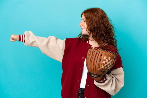 Teenager redhead girl with baseball glove isolated on blue background giving a thumbs up gesture