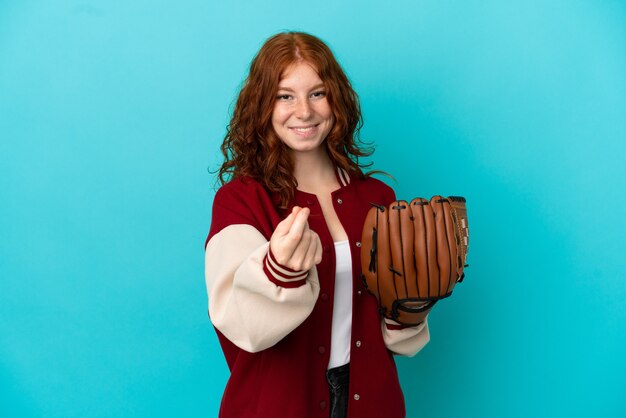 Teenager redhead girl with baseball glove isolated on blue background making money gesture