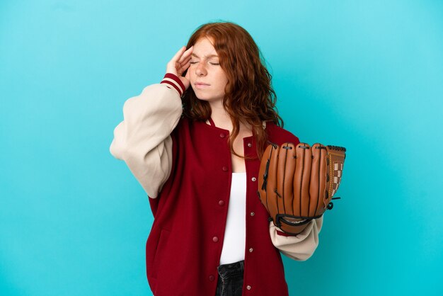 Teenager redhead girl with baseball glove isolated on blue background with headache