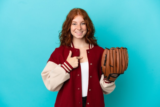 Teenager redhead girl with baseball glove isolated on blue background with surprise facial expression