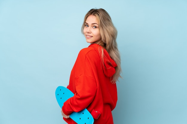 Teenager Russian girl on blue wall with a skate