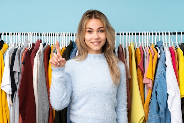 Teenager Russian girl buying some clothes isolated on blue