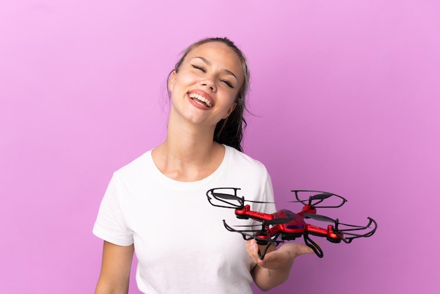 Teenager Russian girl holding a drone isolated on purple background laughing