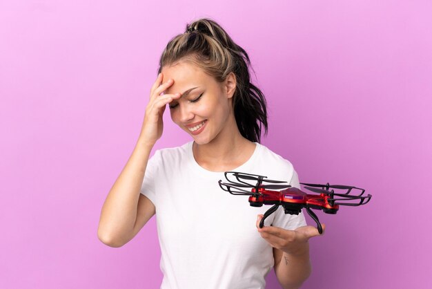 Teenager Russian girl holding a drone isolated on purple background laughing