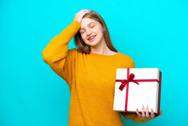 Teenager Russian girl holding a gift isolated on blue background has realized something and intending the solution