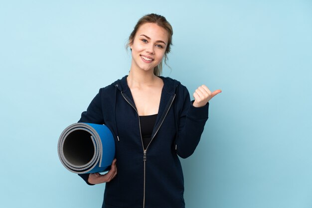 Teenager Russian girl holding mat isolated on blue