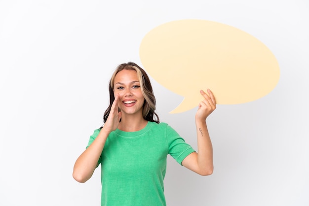 Teenager Russian girl isolated on blue background holding an empty speech bubble and shouting