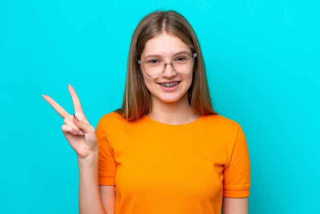 Teenager russian girl isolated on blue background with glasses and doing ok sign
