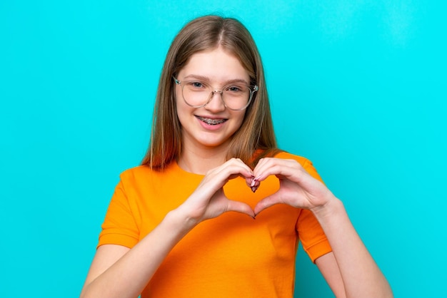 Teenager russian girl isolated on blue background with glasses making heart with hands