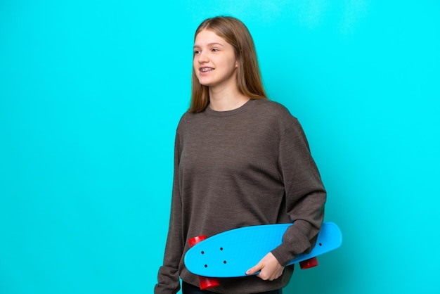 Teenager Russian girl isolated on blue background with a skate