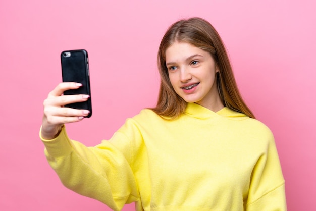 teenager russian girl isolated on pink background making a selfie
