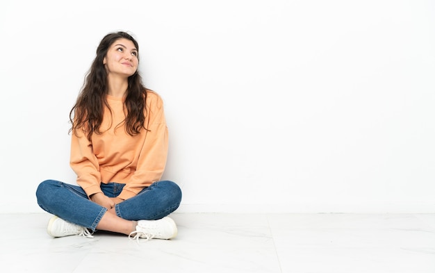 Teenager Russian girl sitting on the floor and looking up