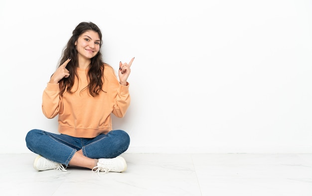 Teenager Russian girl sitting on the floor pointing up a great idea