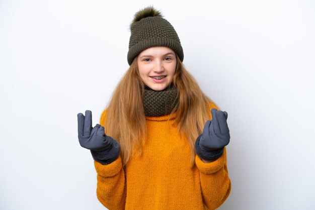 Teenager Russian girl wearing winter jacket isolated on white background making money gesture