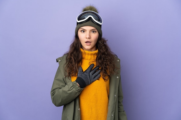 Teenager Russian girl with snowboarding glasses isolated on purple background surprised and shocked while looking right