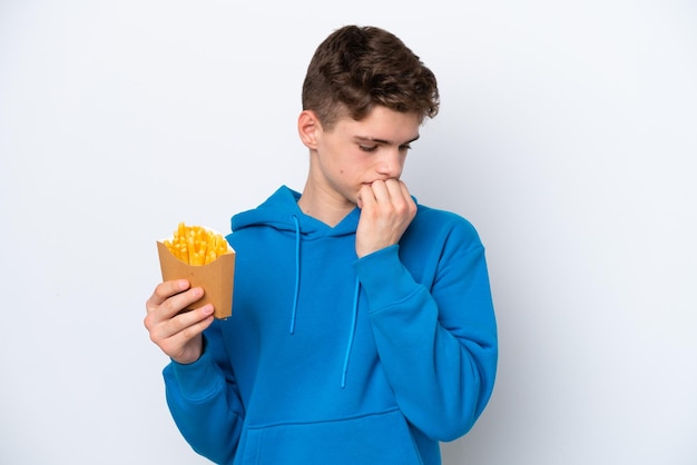 Adolescente uomo russo con patate fritte isolate su sfondo bianco con dubbi