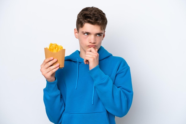 Adolescente uomo russo che tiene patate fritte isolate su sfondo bianco e alzando lo sguardo