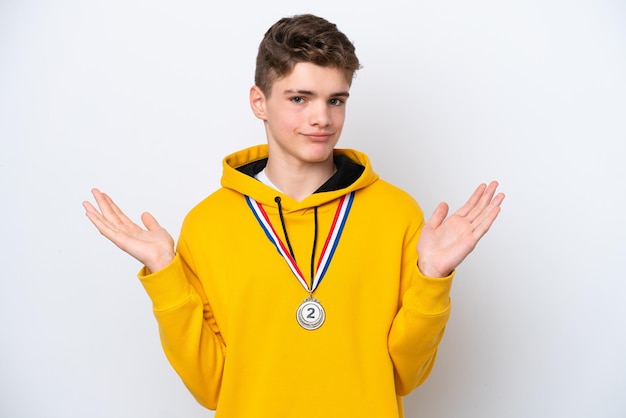 흰색 배경에 격리된 메달을 가진 10대 러시아 남자가 손을 드는 동안 의심을 품고 있습니다.