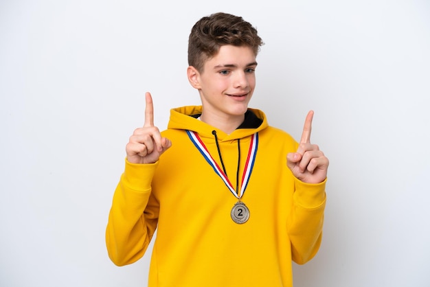 Teenager Russian man with medals isolated on white background pointing up a great idea