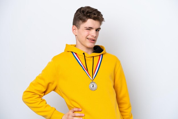 Adolescente uomo russo con medaglie isolate su sfondo bianco che soffre di mal di schiena per aver fatto uno sforzo