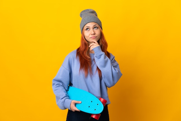 Teenager Russian skater girl isolated on yellow wall and looking up