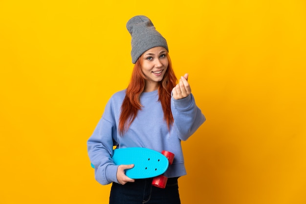 Teenager Russian skater girl isolated on yellow wall making money gesture