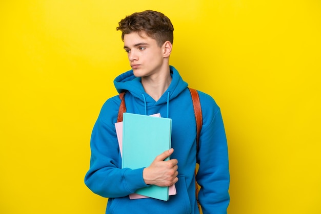 横を見て黄色の背景に分離された10代のロシアの学生の男