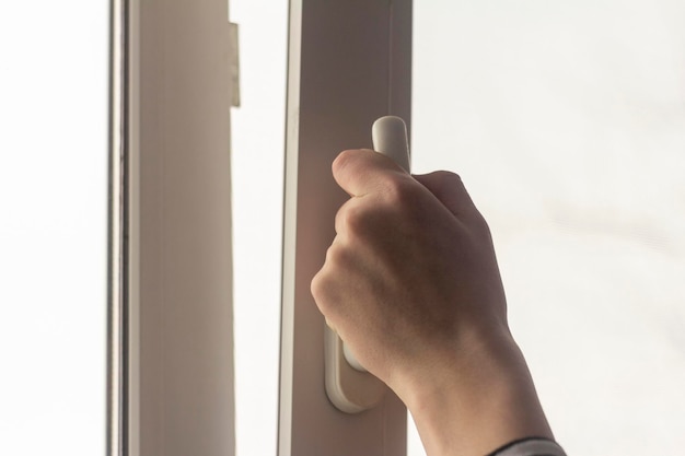 Foto la mano dell'adolescente apre la finestra per arieggiare la stanza