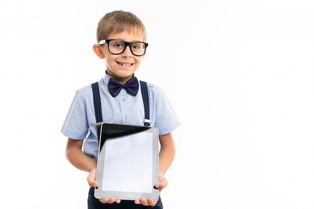 Teenager school boy shows a tablet and smiles, isolated