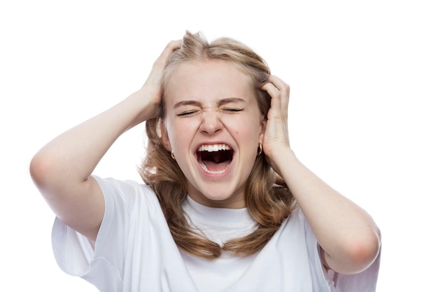 The teenager screams holding his head young girl in a white shirt Negative emotions and stress White background Closeup