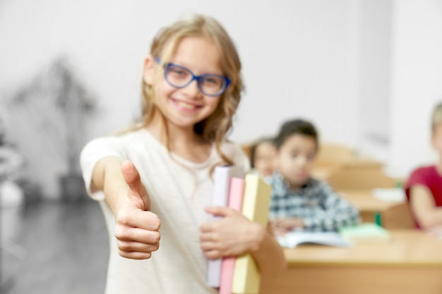 Teenager showing thumb up in classroom at school.