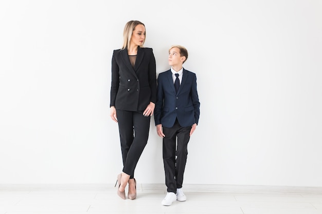 Teenager and single parent - Young mother and son standing together on white wall.