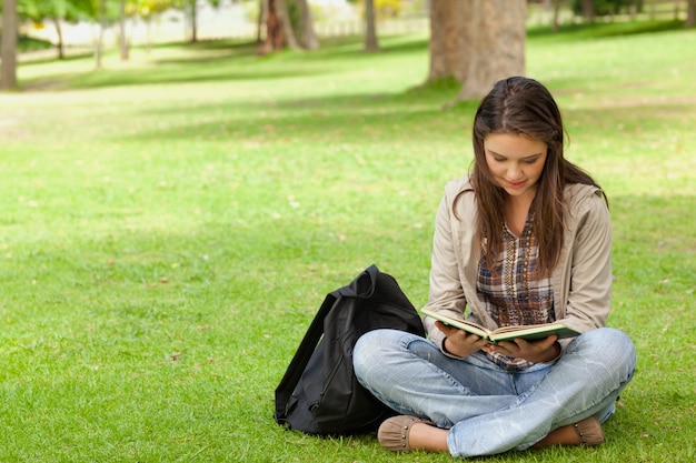 Подросток сидит, читая ее учебник