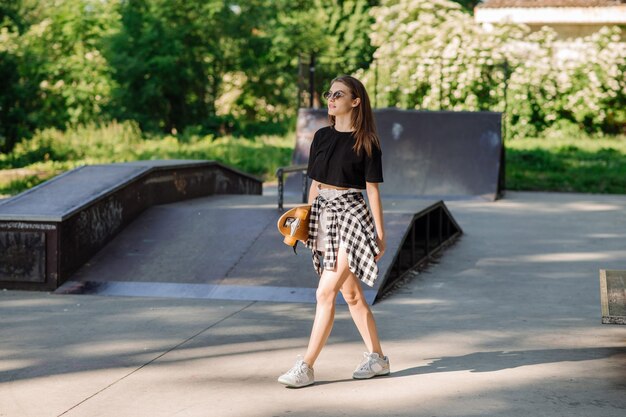 Teenager skater girl holding skateboard on the skaters park