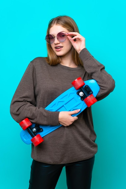 파란색 배경에 고립 된 십 대 스케이팅 소녀