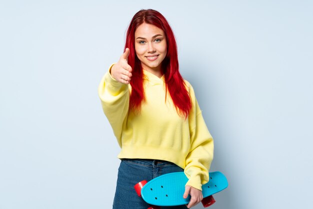 Teenager skater girl isolated on white shaking hands for closing a good deal