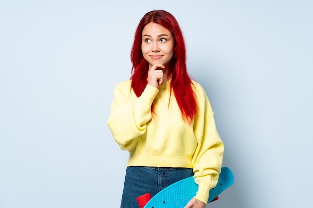 Teenager skater woman isolated on white wall having doubts and thinking