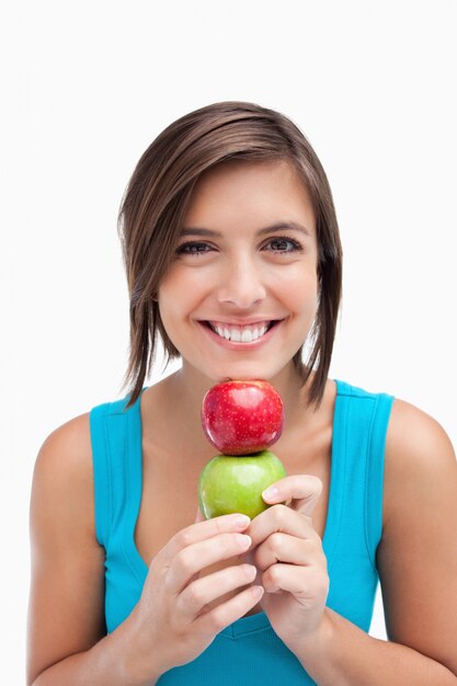 Teenager smiling and holding two apples between her hands and her chin